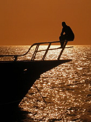 Dive guide relaxing at the end of the day. by James Dawson 